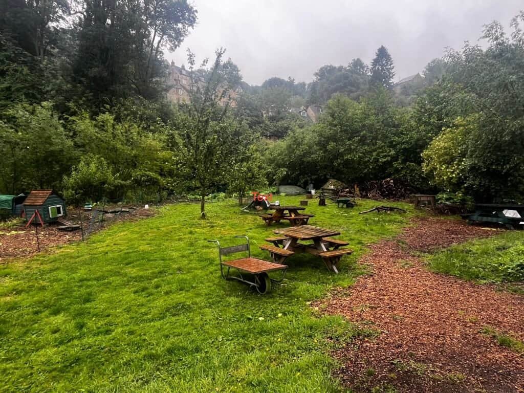 Lush green garden with picnic tables, creating a serene outdoor biodynamic farm setting.