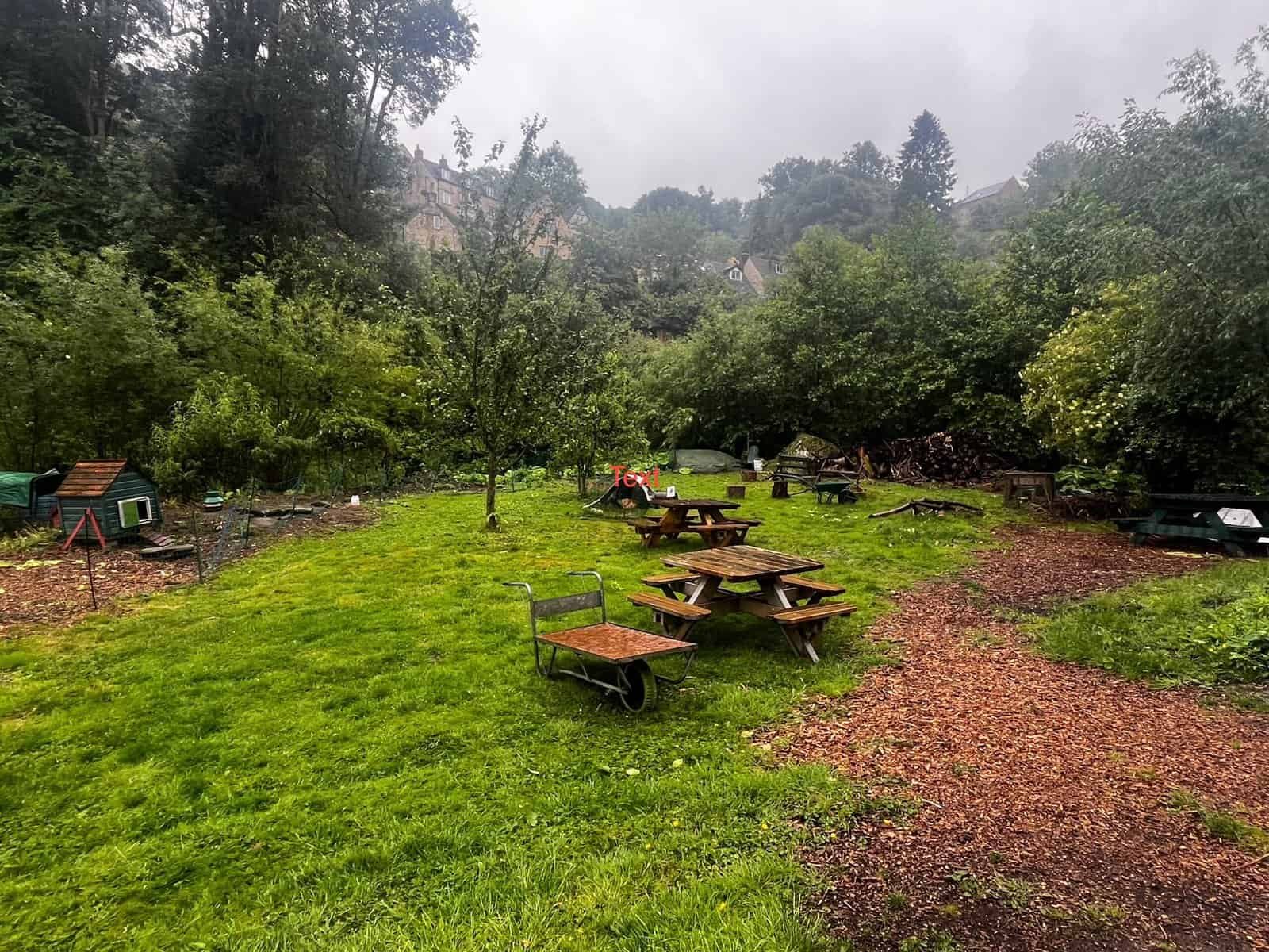 Lush green garden with picnic tables, creating a serene outdoor biodynamic farm setting.